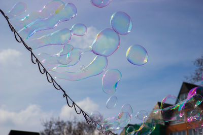 Low angle view of bubbles against rainbow in sky