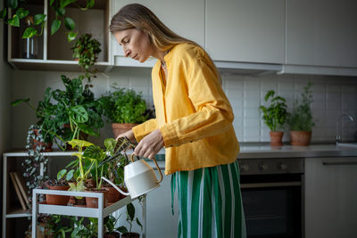 Plant lover woman having ecological hobby of plants growing taking care, watering potted houseplants