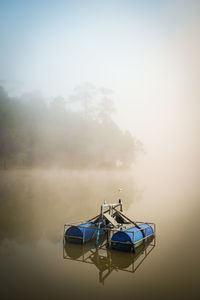 Boat moored on lake against sky