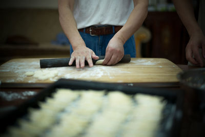 Midsection of man rolling dough at table