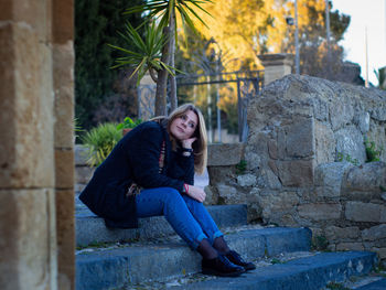 Young woman sitting on stone wall