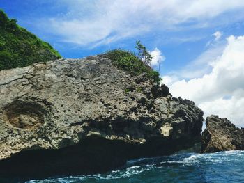 Rock formation by sea against sky