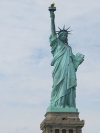 Low angle view of statue of liberty against cloudy sky