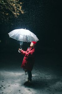 Woman with umbrella during snowfall at night