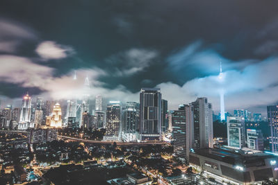 Illuminated cityscape against cloudy sky