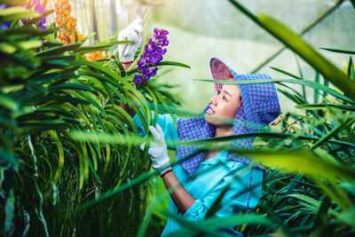 Female researcher examining flowers in greenhouse