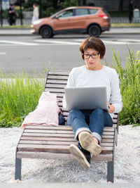 Young woman using mobile phone while sitting on bench