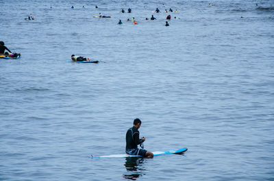 Man sitting on surfboard in sea