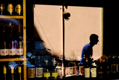 Bottles seen through glass with reflection of man