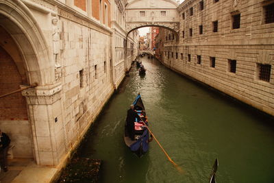 High angle view of man in gondola on canal amidst buildings