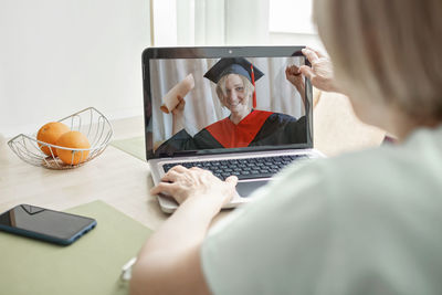 Woman using phone while sitting on table