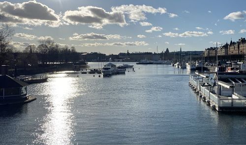Sailboats moored in harbor against sky in city