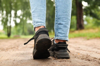 Fashion designer women's sneaker with high sole. female sports black shoe on forest background. 