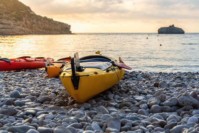 Pebble  beach with empty kayaks at sunrise.