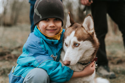 Kid and his friend husky siberian dog. portrait little child boy hugging cute white brown animal pet