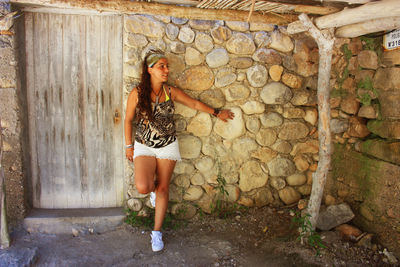 Full length portrait of woman standing against wall