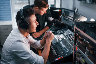 Conception of teamwork. two guys is indoors in the radio studio is busy by broadcast.