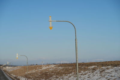 Street lights on railroad track against clear blue sky