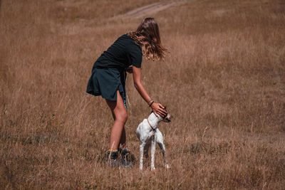 Rear view of man with dog running on field