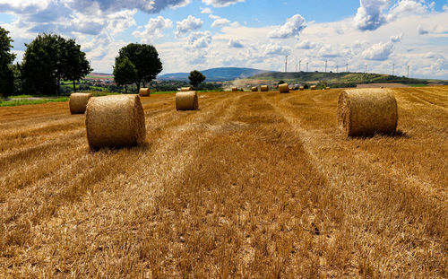 Hay bales on field against sky