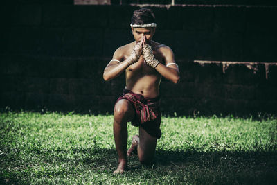 Full length of shirtless man standing on field