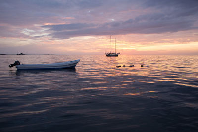 Sailboat sailing in sea at sunset