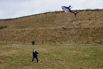 Full length of man paragliding on field against sky