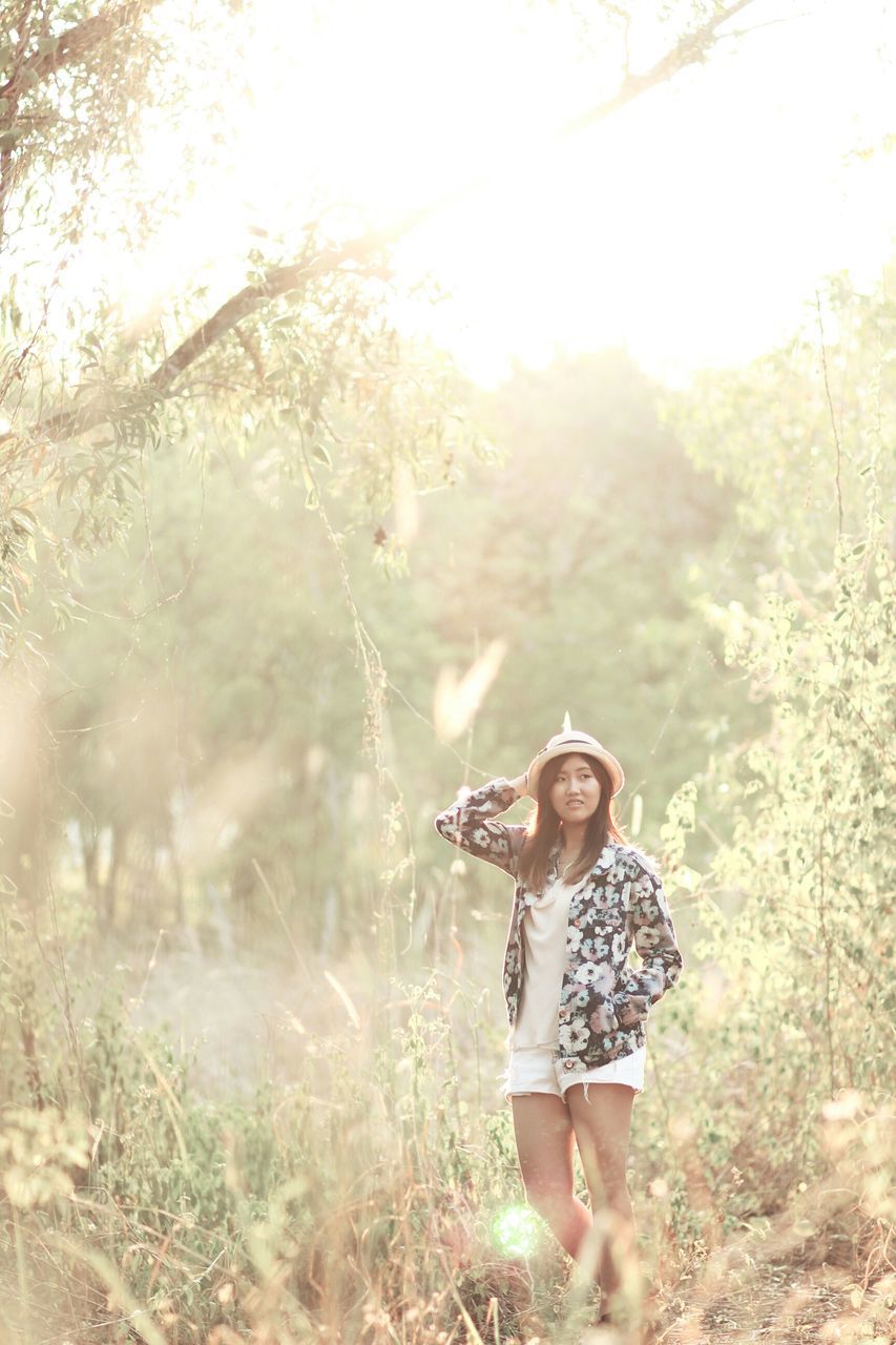 lifestyles, leisure activity, young adult, casual clothing, person, young women, standing, looking at camera, front view, portrait, three quarter length, tree, field, holding, full length, grass, nature