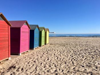 Beach huts against clear blue sky