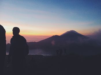 Silhouette of man standing on mountain at sunset