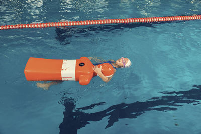 High angle view of girl swimming with dummy in pool