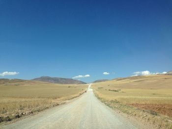 Road passing through landscape against blue sky