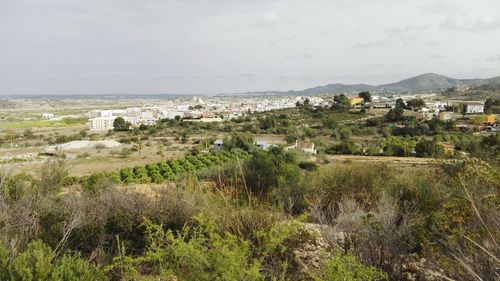 Aerial view of townscape by sea against sky