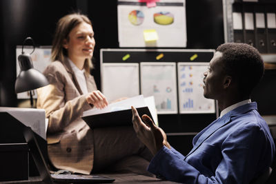 Rear view of man using digital tablet while sitting in office