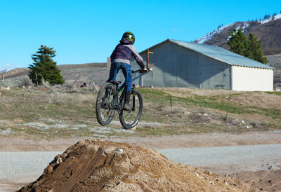 Boy on bicycle jumping over street during sunny day