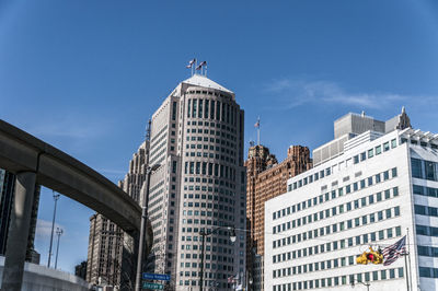 Low angle view of buildings and monorail against blue sky