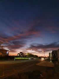 Illuminated city against sky at sunset