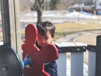 Portrait of boy standing on play equipment at playground