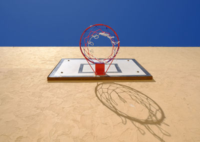 Low angle view of basketball hoop on wall against clear blue sky during sunny day