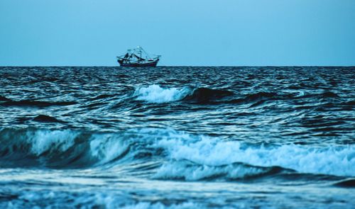 Boat sailing in sea against clear sky