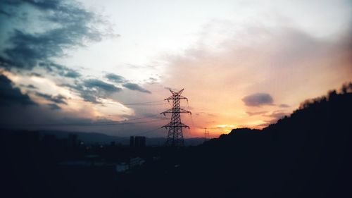 Silhouette electricity pylon against sky during sunset