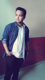 Portrait of young man standing against wall