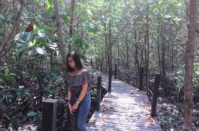 Woman standing on footbridge in forest