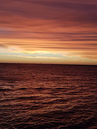 Scenic view of sea against dramatic sky during sunset