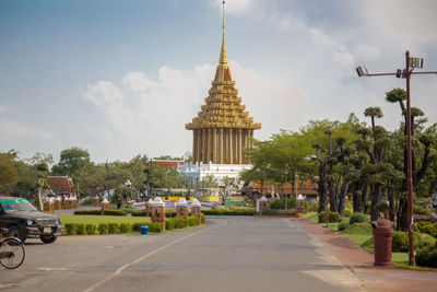 Road amidst trees and buildings against sky