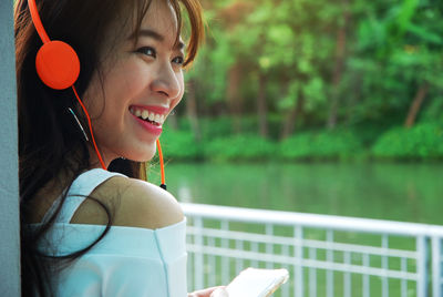 Smiling young woman listening music through headphones