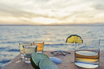 Close-up of drink on table at beach against sky