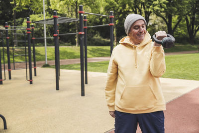 Smiling senior man exercising with kettlebell at park