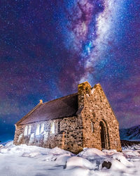 Built structure on snow covered field against sky at night