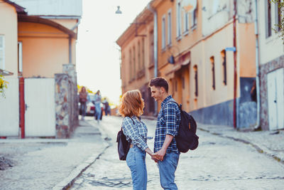 Rear view of friends standing on street in city